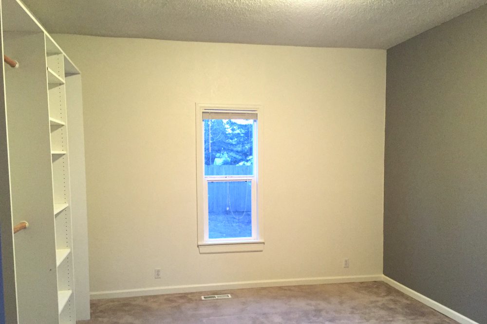 Bedroom with built-in closet shelving and a large window